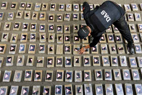 Colombia seize 738 kg drugs A Officer from the Colombian intellegence agency stacking the drugs, with an estimated street value of $25 M - Photo: EFE / CARLOS ORTEGA