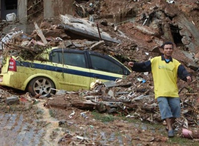 Man walking away from a car buried under mud and rubble - Image by: Silvia Izquierdo/Associated Press