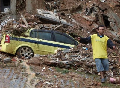 brazil mudslide - nationalturk Man walking away from a car buried under mud and rubble - Image by: Silvia Izquierdo/Associated Press