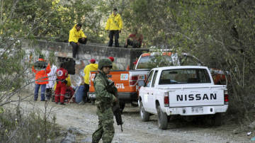 mexico-mine Workers are working in the mine where 55 bodies were found with a soldier waiting guard - Photo by : Margarito Perez / Reuters