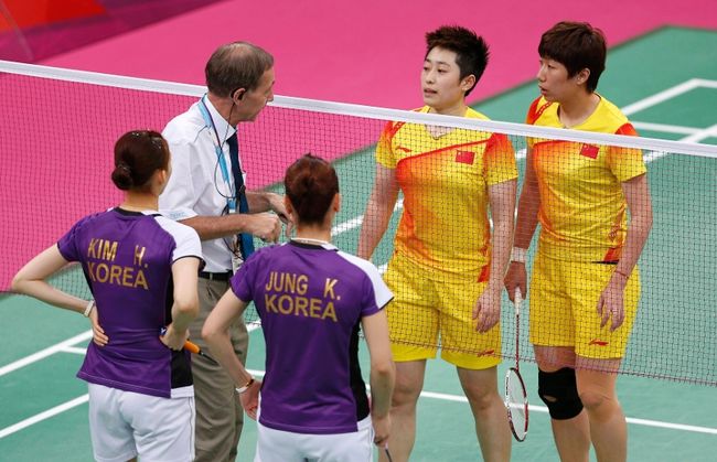 the badminton referee speaks to players from China and South Korea during their farcical women's doubles Group A badminton match during the London 2012 Olympic Games
