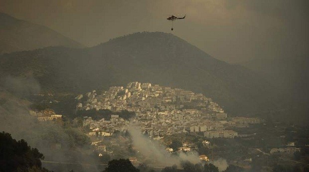 An helicopter of the fire brigade prepares to pour water to extinguish a wildfire in Ojen, near the town of Malaga, on August 31, 2012. Some 4,000 people were evacuated from the area. More than 250 firefighters on the ground, backed by eight planes and nine helicopters, battled the blaze after hot, dry winds sent it racing through tinder-dry forest in southern Spain.   