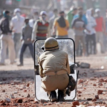 Policeman ducks while youth pelt stones on him during clashes in Indian administered Kashmir. File Pic