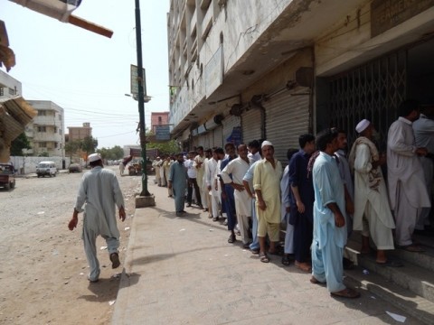 Pakistani people waiting in queue outside a polling station to cast their votes.