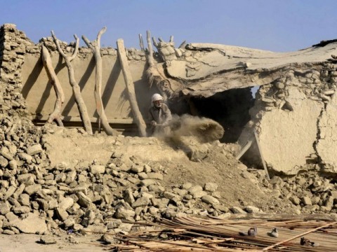 An elderly man clears debris from collapsed house in Pakistan.