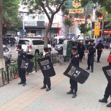 Chinese policemen blocking road and looking towards blast site.