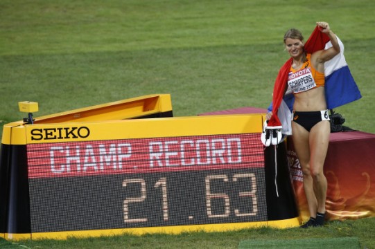 Gold medal winner Dafne Schippers of the Netherlands celebrates with the Dutch flag as she poses with a sign with a new Championship Record after winning the women's 200m final at the World Athletics Championships at the Bird's Nest stadium in Beijing, Friday, Aug. 28, 2015. (AP Photo/Mark Schiefelbein)